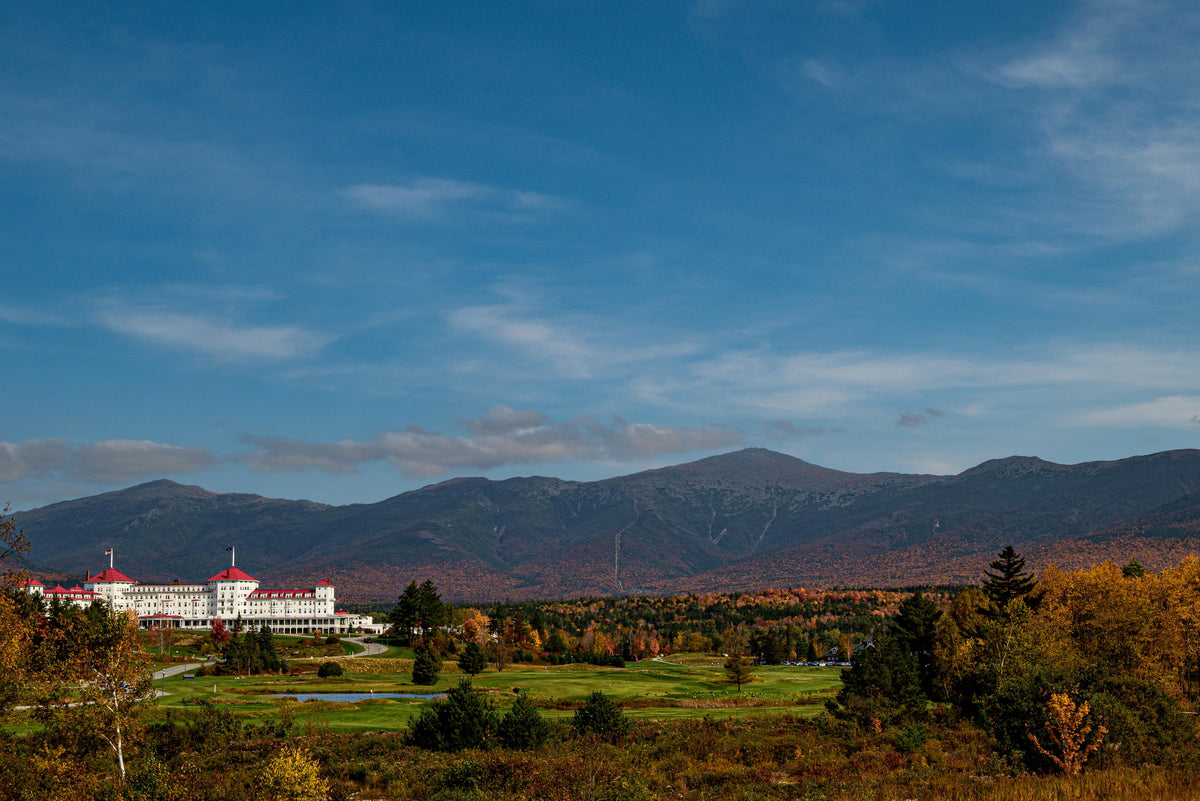 Mount Washington Hotel Autumn photography print with white facade and red roofs, backed by forested mountains and fall foliage.