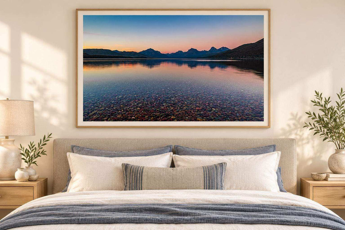 Glacier National Park Print featuring a fine art lake landscape with clear blue water, colorful shoreline stones, and pink sunset skies