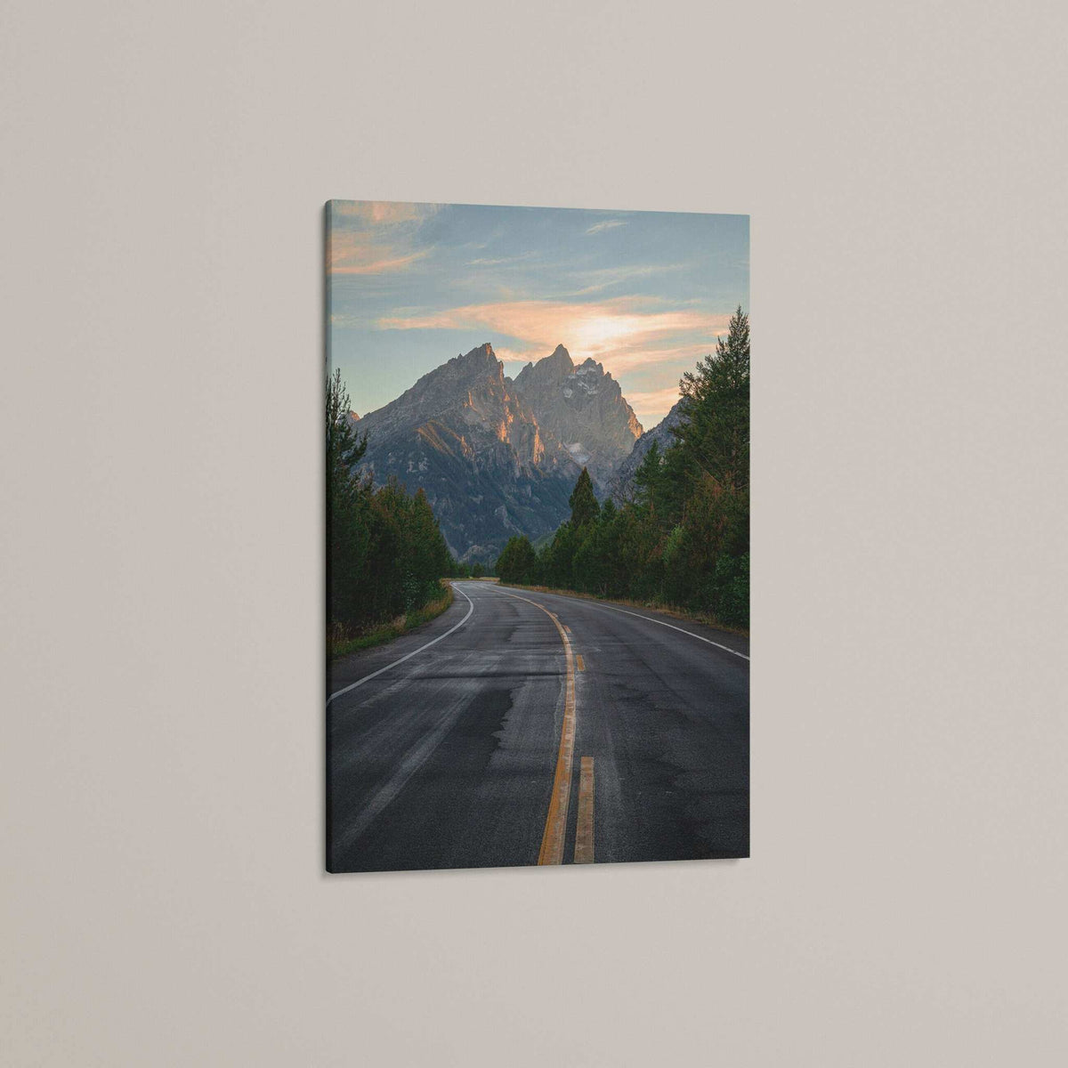 Grand Teton Wall Art featuring a mountain road print with a winding gray highway, evergreen trees, and sunset-lit peaks