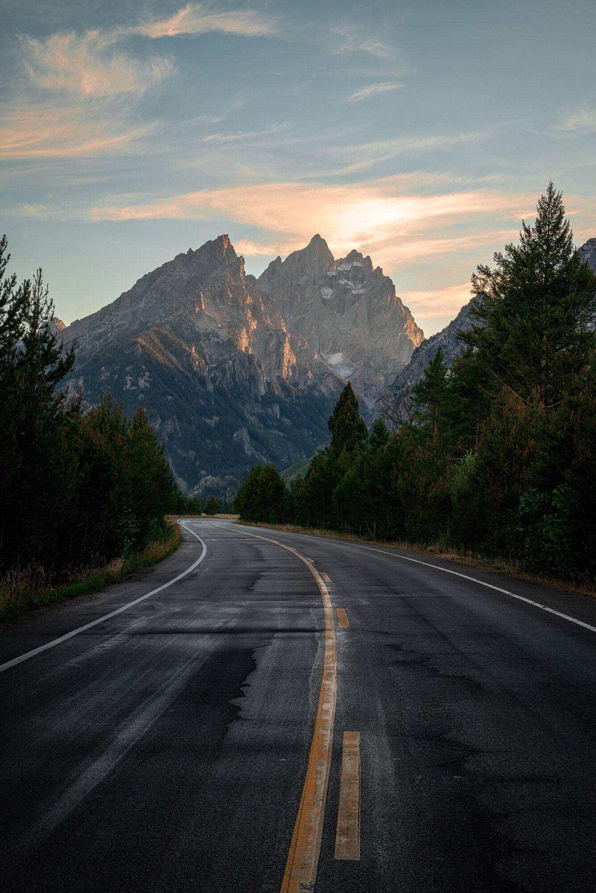 Grand Teton Wall Art featuring a mountain landscape photograph with a winding road, forest, and jagged peaks at sunset