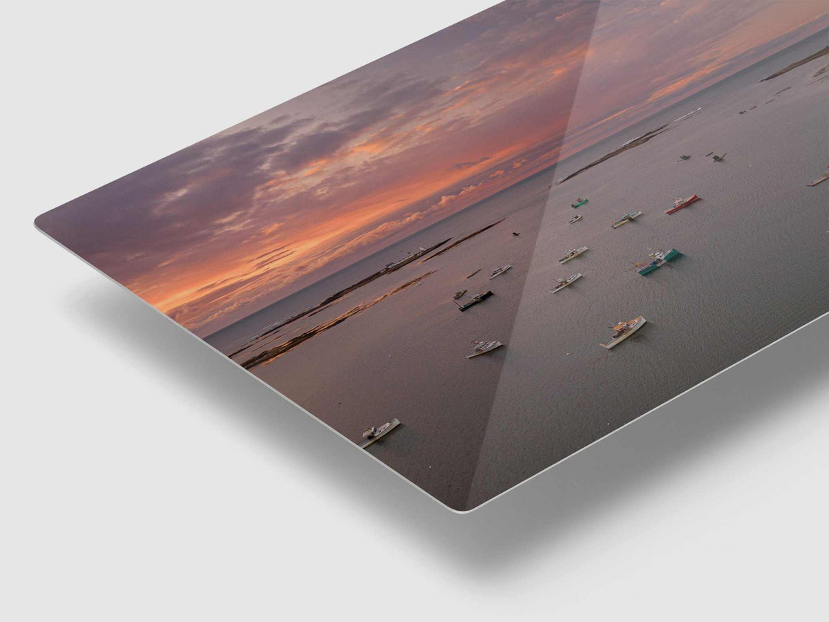Maine Coastal Wall Art metal print showing an aerial harbor with fishing boats beneath a warm orange and purple sunrise sky