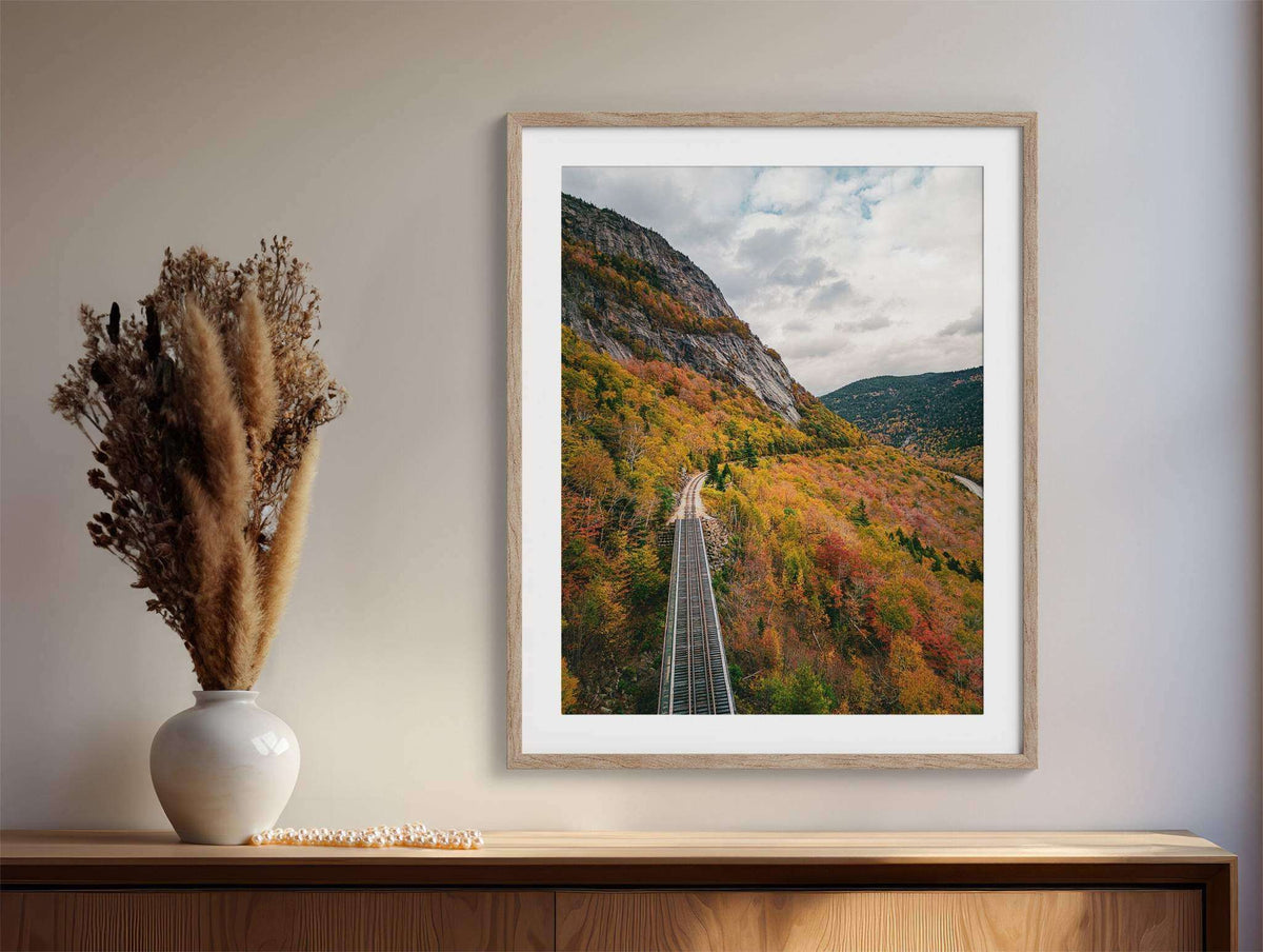 New Hampshire Fall Foliage Print featuring railroad tracks winding through orange and gold autumn trees in a mountain valley