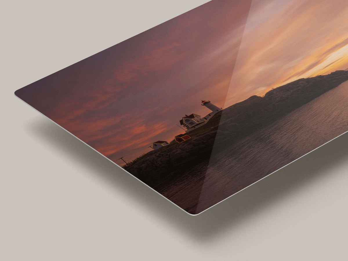Nubble Lighthouse Wall Art metal print with a coastal lighthouse on dark rocky shore beneath a pink and orange sunrise sky