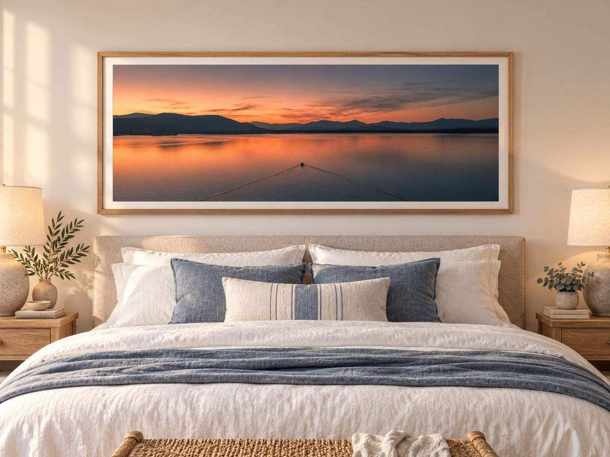Ossipee Lake Wall Art in a wood frame, showing calm water, distant mountain silhouettes and a pink-orange sunset