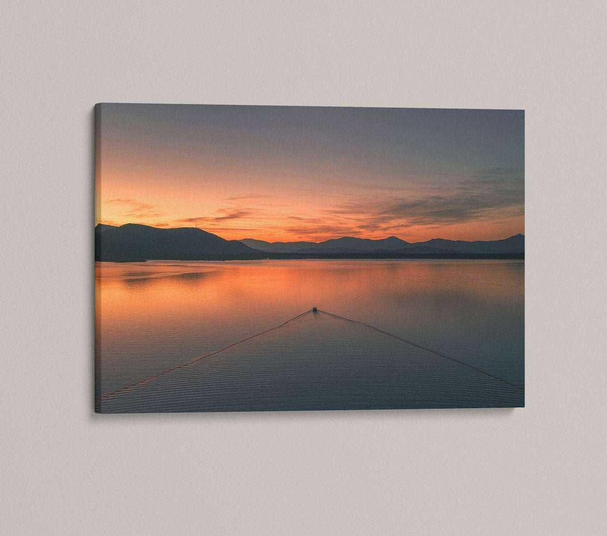 Ossipee Lake Wall Art shows a calm lake at sunset, with orange-pink skies, mountain silhouettes, and a small boat.