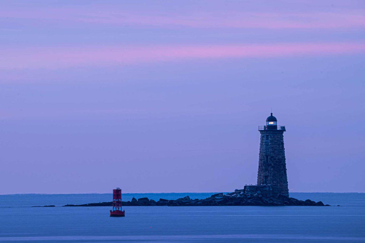 Whaleback Lighthouse Print featuring a dark stone lighthouse on rocky water beneath a lavender and pink pastel sky